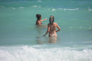 Two young women jump into the waves of the sea. Fun at the sea, on vacation.