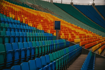 Obraz premium Colorful stadium seating in blue, green, orange, and yellow, viewed from a low angle looking up the stands