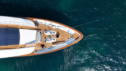 Aerial drone top down photo of luxury yacht with wooden deck anchored in deep blue Aegean sea, Mykonos island, Cyclades, Greece