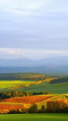 Fototapeta premium Autumn landscape with colorful fields and distant mountains
