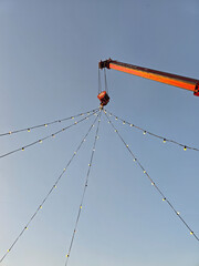 Fairy lights on a crane cable car on blue sky background