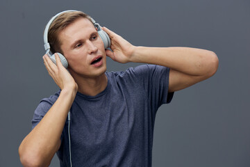 young caucasian man wearing headphones listening music enjoy sound closeup gray background...