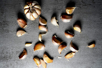 Aromatic Garlic Cloves: Freshly Harvested Garlic Bulb and Separated Cloves on a Dark Grey Background
