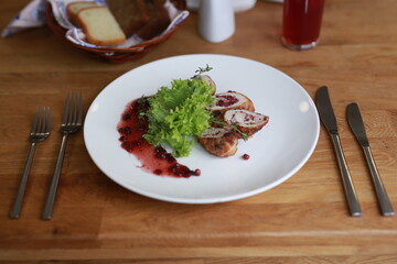 Gourmet Chicken Dish with Cranberry Sauce and Leafy Greens in Fine Dining Setting