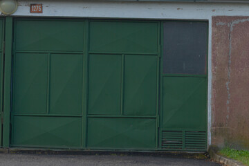 A close-up view of a green industrial garage door featuring a metal framework, set against a...