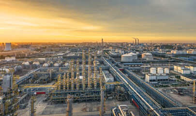 Panoramic view of a massive petrochemical industrial zone illuminated by the warm golden light of a...