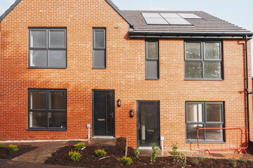 New two-story brick house features modern design and solar panels in a residential neighborhood during late afternoon light