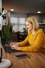 Creative workspace where a focused woman types on her laptop while enjoying a cozy indoor setting...