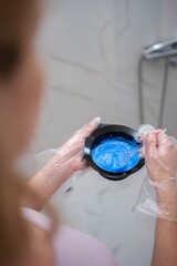 Woman preparing blue hair dye in bathroom