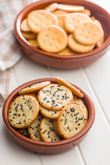 Crispy round salted crackers in bowl on white table.