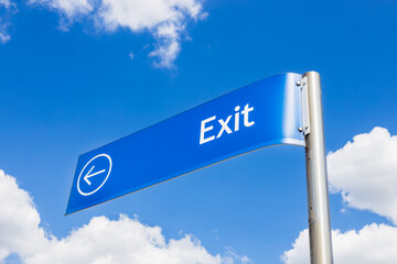Blue Exit Road Sign with Arrow Against Bright Sky