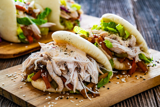 Bao Buns with pulled chicken and vegetables on wooden table	