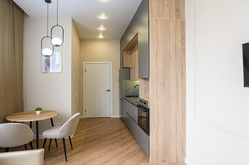 Modern kitchen & dining area with wood floors, gray cabinets, and a round table with pendant lights