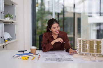 Asian architect professional woman designs modern buildings plans reviews blueprints creates...