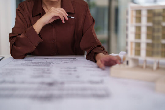 Asian adult architect woman designs architectural blueprints building models focusing construction planning development professional office workplace