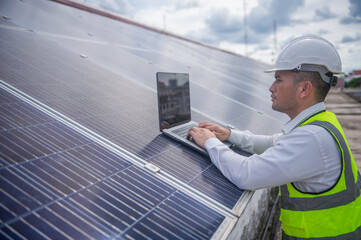 An expert electrician is inspecting the solar panels on the rooftop of an office building for...