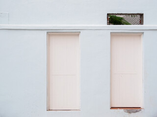 Light blue walls with two wooden white doors and a rectangle hole.