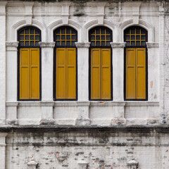 Obraz premium Yellow wooden windows closed with white rustic walls.