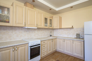 bright kitchen features light wood cabinets, tiled backsplash, and a white stove and refrigerator. The floor is a wood pattern