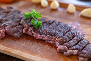 Sliced medium rare brisket steak served on wooden plate