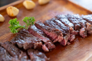 Sliced medium rare brisket steak served on wooden plate