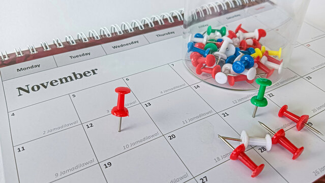 A collection of colorful push pins scattered across a calendar, symbolizing reminders, scheduling, and organization for important dates.