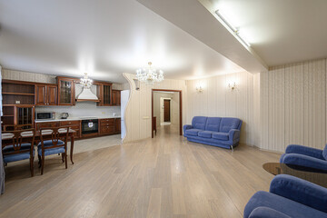 spacious, well-lit interior featuring an open kitchen, dining area, and living room. The color palette includes brown, blue, and beige