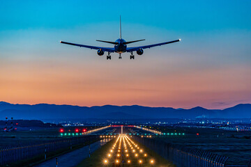 夕焼けの中空港へ着陸する旅客機　飛行機　トワイライト