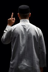 Man in traditional Islamic clothing points finger up, signifying unity, faith, and religious devotion