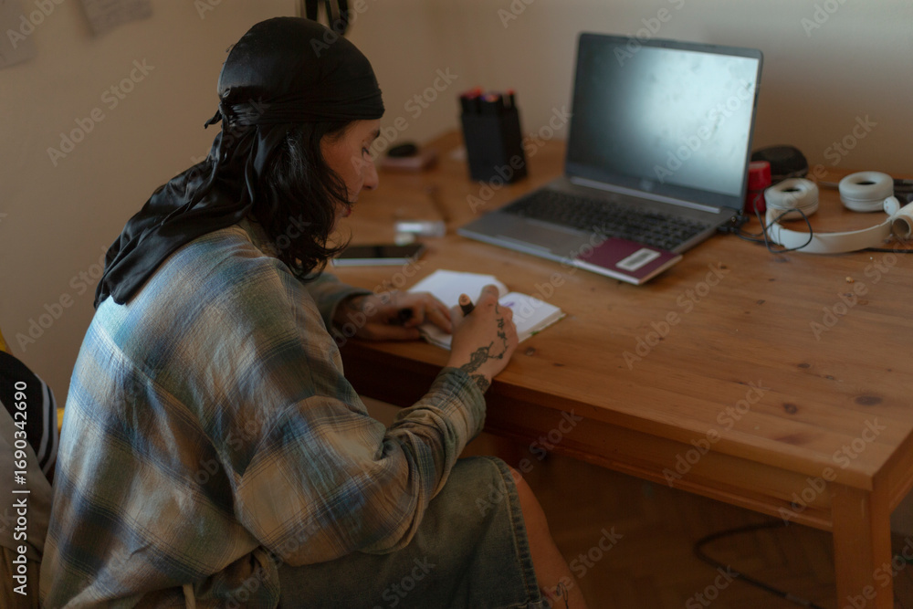 Poster a man is comfortably seated at a desk where a laptop is set up, allowing him to work or browse the i