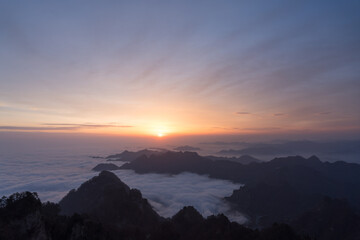 Golden light illuminates Wudang Mountain in China as the sun rises above a serene, misty cloudscape.