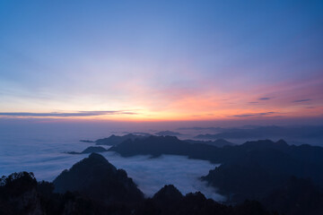 Wudang Mountain in China displays a breathtaking sunrise, with majestic peaks emerging from a vast...