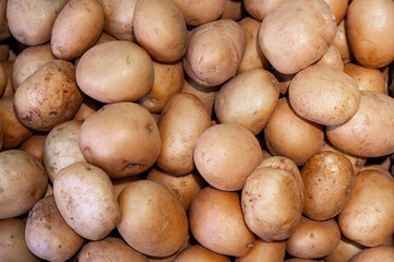 Lots of fresh potatoes as background, top view. Potatoes on the counter of a vegetable store. Wholesale purchase