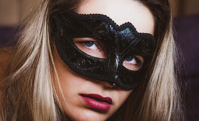 Sexy nude young woman with black mask posing in the bedroom