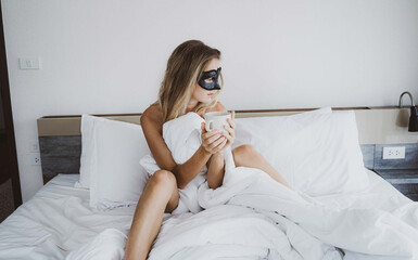 Sexy nude young woman with black mask posing in the bedroom