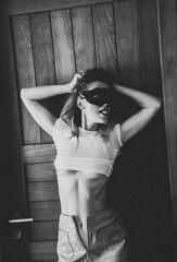 Sexy nude young woman with black mask posing near the doors