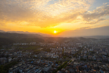 Wudang town in China offers a vast urban landscape view from above, as golden sunset light illuminates buildings and distant mountains.
