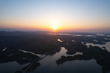 Golden sunset hues illuminate the extensive reservoir, revealing numerous green islands and a...