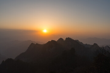 Golden sunlight illuminates the majestic Wudang Mountain peaks in China, casting a warm glow over the natural landscape.
