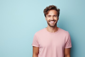 Smiling young man with stylish hair standing against a light blue background, exuding confidence and warmth
