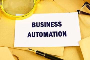 The concept of the info business. The text of BUSINESS AUTOMATION is written on a business card against the background of postal envelopes