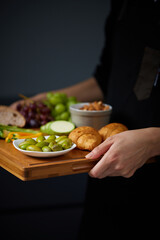 Fresh fruit and vegetable mix, Woman's Hands Carrying a Wooden Board with Assorted Appetizers and Breads