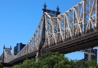 Intricate steelwork of the Queensboro Bridge and the massive cantilever truss structure and blue sky in New York City