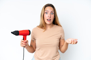 Young caucasian woman holding a hairdryer isolated on white background with shocked facial...