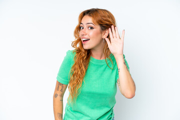 Young caucasian woman isolated on white background listening to something by putting hand on the ear