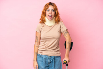 Young caucasian woman wearing neck brace isolated on pink background with surprise facial expression