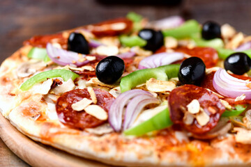 Pizza with chorizo ​​sausage, mozzarella cheese, green pepper and black olives. Rustic wooden background. Soft focus.	