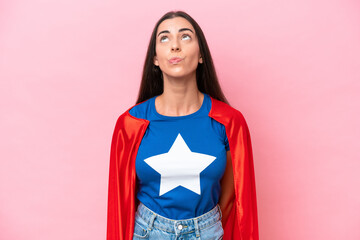 Super Hero Caucasian woman isolated on pink background and looking up