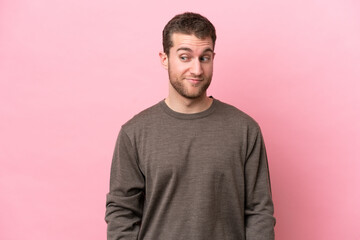 Fototapeta premium Young caucasian man isolated on pink background making doubts gesture looking side