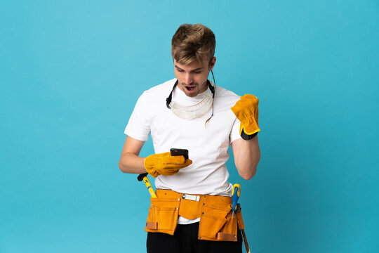 Young electrician man over isolated wall surprised and sending a message
